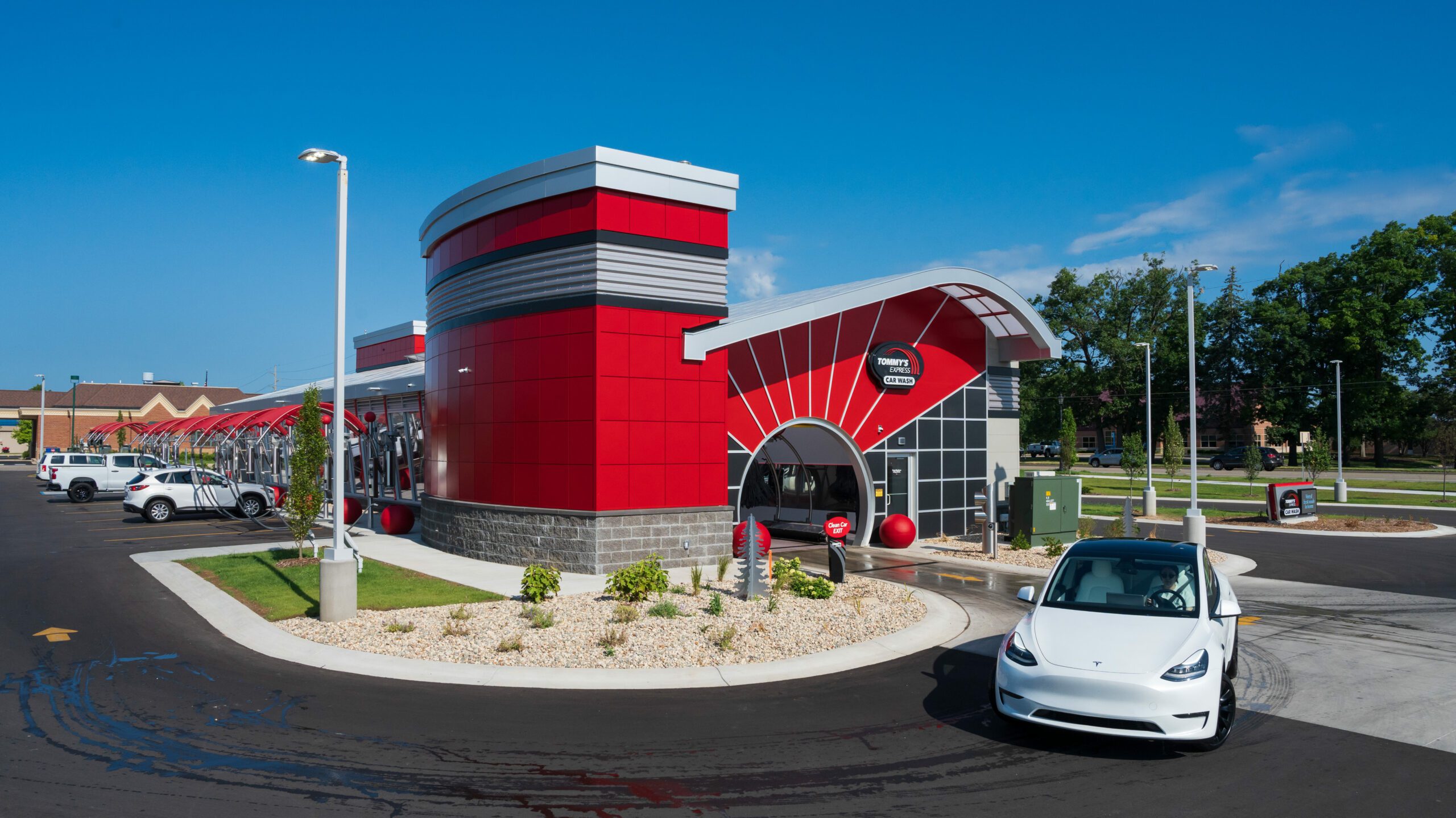 White Tesla leaving Tommy's Express Car Wash on a sunny day