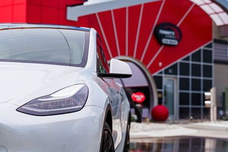 White Tesla sedan leaving Tommy's Express car wash tunnel