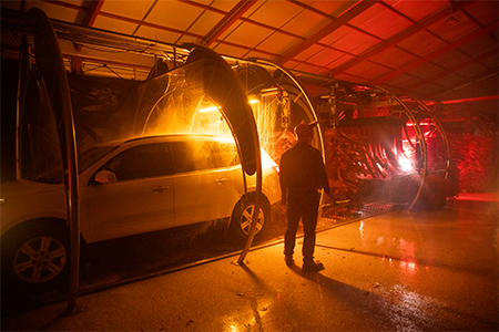 person in custome standing in dark car wash tunnel during tunnel of terror
