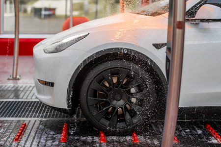 Side view of white Tesla in a tommy's express car wash tunnel